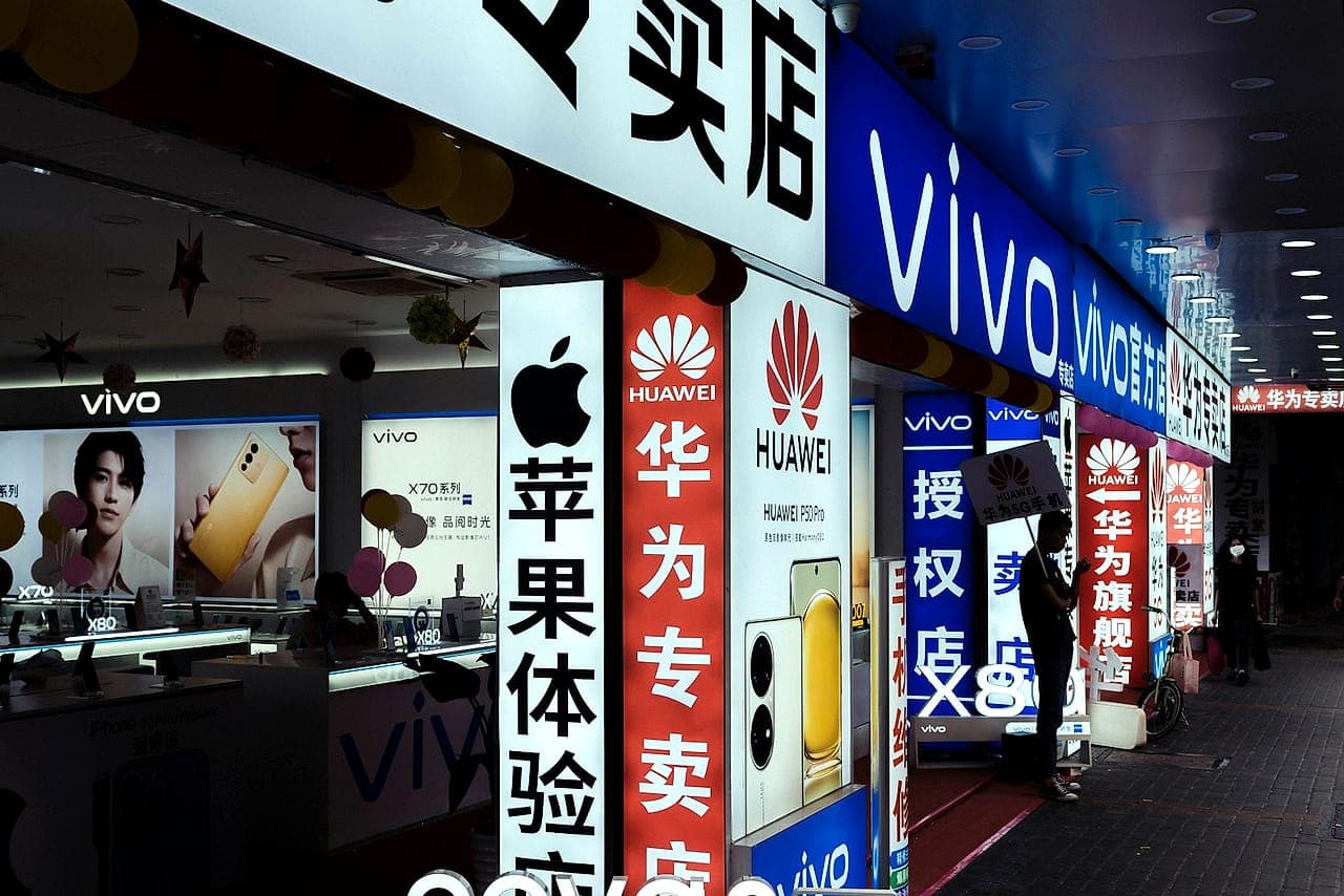 Illuminated phone-brand signage along an electronics retail street in Guangzhou, China