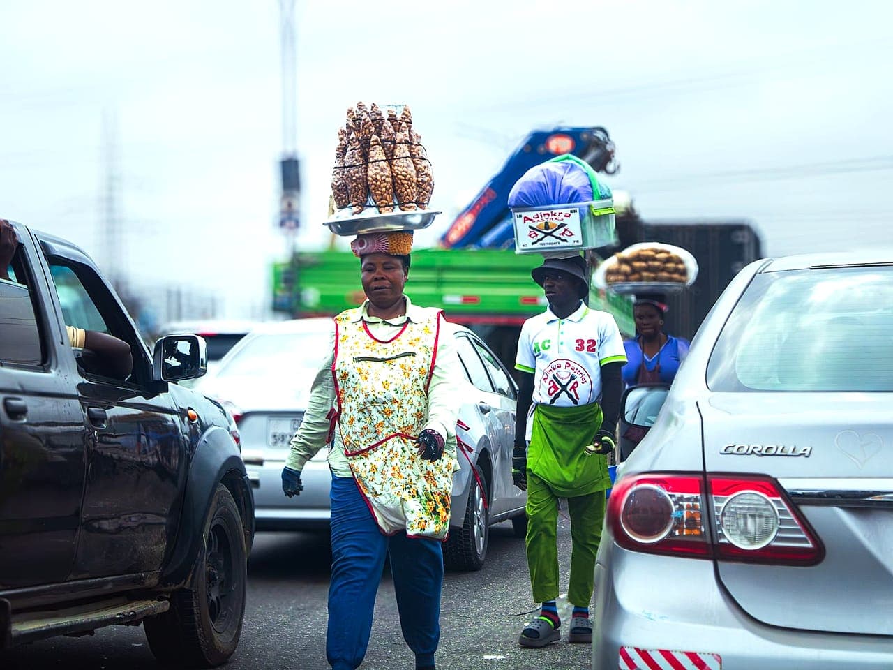 Street vendors carrying goods between traffic in Accra, Ghana